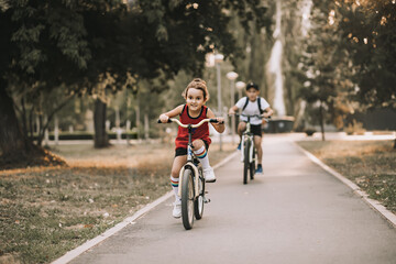 Two little boy and girl cyclists riding their bikes and enjoy having fun. Kid outdoors sport summer activity.