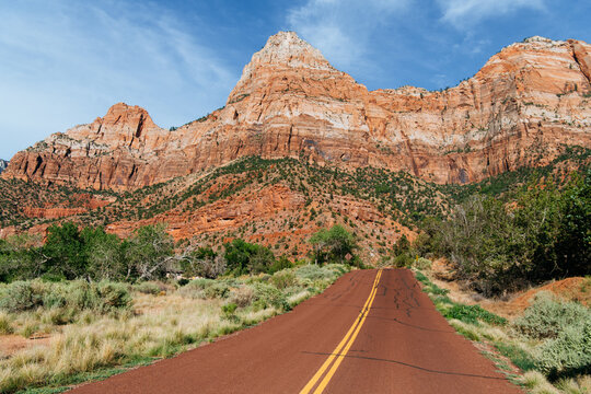 The Watchman formation towers over a brown road in Zion National Park, Utah