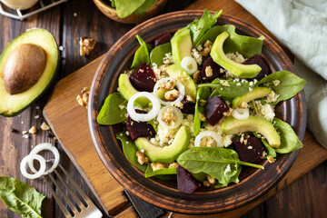 Couscous with avocado, beet, green beans, spinach on a rustic wooden table. Vegan food.