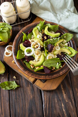 Couscous with avocado, beet, green beans, spinach on a rustic wooden table. Vegan food. Copy space.