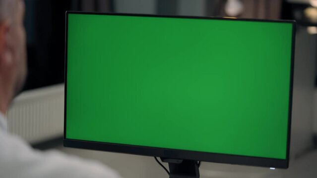 Man Working At Computer With Green Mock Up Screen in Home. Close Up Desktop Computer Monitor with Mock Up Green Screen Chroma Key Display
