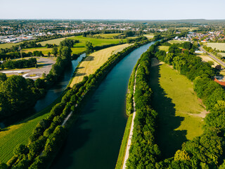 Summer aerial drone view landscape navigable river with bridges, agricultural fields and forests and farmers houses in Germany countryside. 