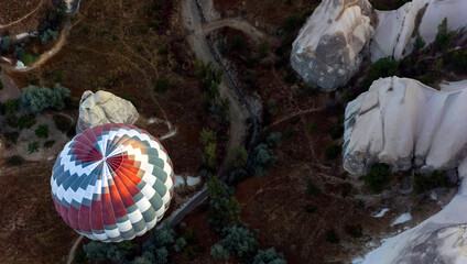 Colorful hot air balloon flying over valley with white rocks in Cappadocia, Turkey, top view