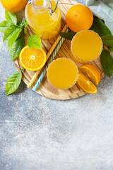 Ripe oranges and two glasses of fresh juice squeezed orange juice on a stone tabletop. View from above. Copy space.