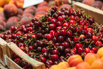 Fresh ripe red cherry or cherries fruit in a wooden box in a farmer agricultural open air market,...