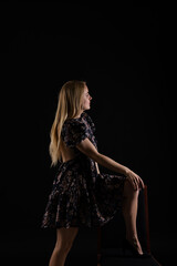 Fototapeta premium blonde standing on a chair with her back on a black background