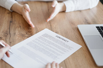 Business people signing contract papers while sitting at the wooden table in office, closeup. Partners or lawyers working together at meeting. Teamwork, partnership, success concept.