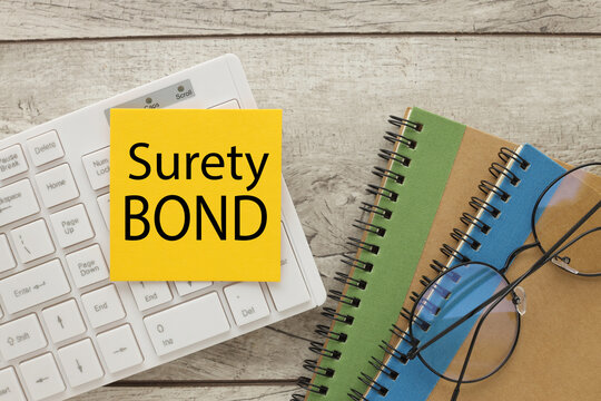 Surety bonds text on yellow sticker on white keyboard.