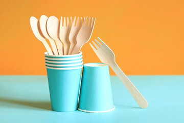 Wooden disposable forks and spoons in a blue paper cup, side view. Eco friendly disposable kitchen...