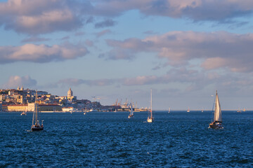 View of Lisbon over Tagus river from Almada with yachts tourist boats at sunset with dramatic sky. Lisbon, Portugal