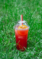 Red aperol spritz  summer sweet drink on green lawn.