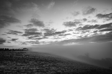 Thick morning fog over valleys, countryside Tuscany, Italy, black and white picture