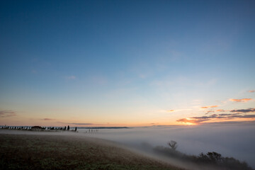 Fototapeta premium Thick morning fog over valleys, countryside Tuscany, Italy