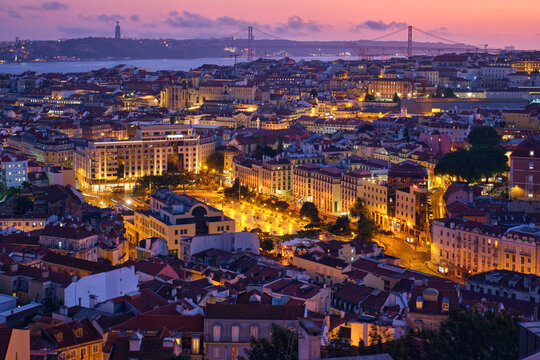 Evening aerial view of Lisbon famous view from Miradouro da Senhora do Monte tourist viewpoint of Alfama and Mauraria old city districts, 25th of April Bridge in the evening twilight. Lisbon, Portugal