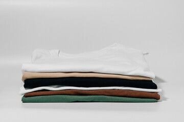 T-shirts folded in a neat stack on a white isolated background. The concept of changing the...