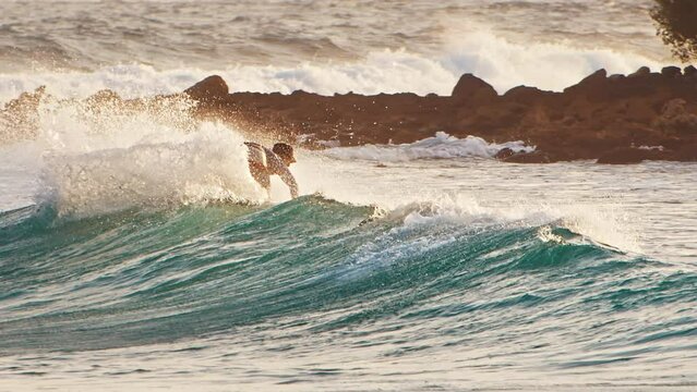 Male surfer rides the wave in the ocean and does sharp turn