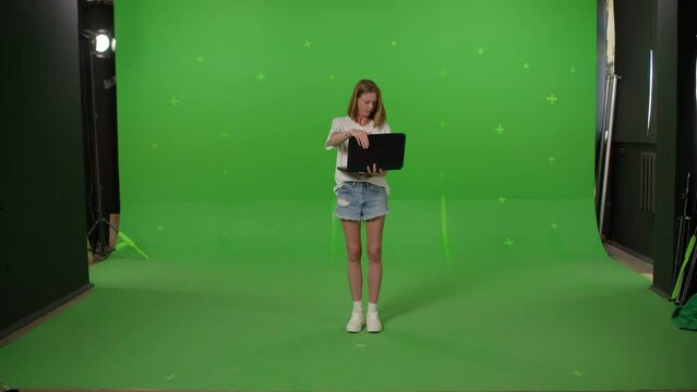 Angry worker breaking laptop. Young woman throwing the computer on Green screen background, chroma key.