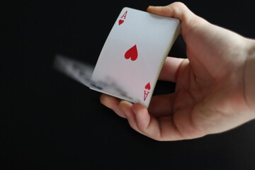 blurry deck of cards being shuffled by a hand in a black background 