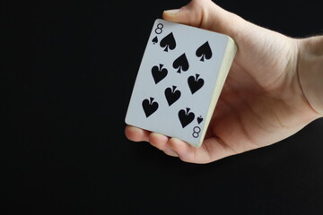 black and white deck of cards holded in a magician's hand in a black background 