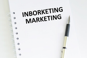 Inborketing marketing inscription on a notebook on a table next to a pen