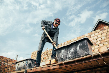 An experienced worker works on the construction of a brick house
