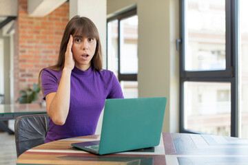 young pretty woman looking happy, astonished and surprised.  desk laptop concept