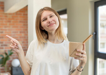 young pretty woman smiling cheerfully, feeling happy and pointing to the side ramen noonles concept