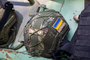 A military helmet of a Ukrainian soldier with a bulletproof vest on an armored car. The flag of Ukraine as a symbol.
