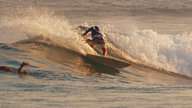 Male surfer rides the wave in the ocean and does sharp turn