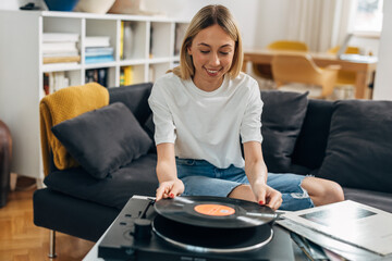 A happy young woman plays music from vinyl records.