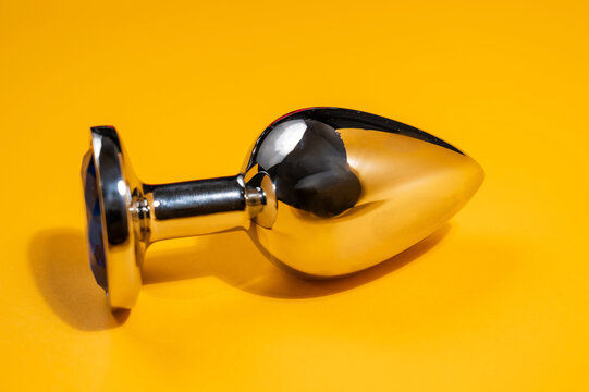 Steel anal plug on an orange background. Sex toy for alternative sex.