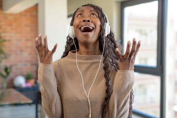 black afro woman screaming with hands up in the air. listening music concept