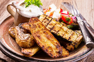 Traditional grilled vegetable with barbecue potatoes an tzatziki served as close-up on a rustic...
