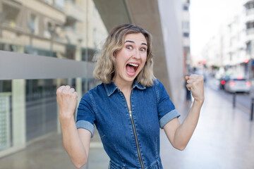 pretty woman feeling shocked, excited and happy, laughing and celebrating success, saying wow!
