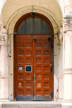 Old wooden double doors with arched top and square ornamentation