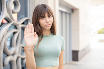 pretty young woman looking serious, stern, displeased and angry showing open palm making stop gesture