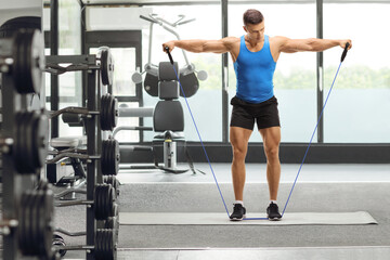 Muscular guy exercising with a resistance band at the gym