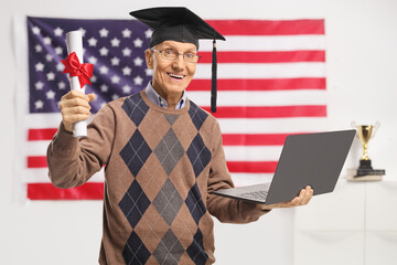 Senior man holding a graduation degree diploma and a laptop computer in front of USA flag