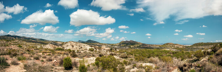 Panoramic and desert landscape of the countryside of Murcia, with the sea in the background and a bright sky with clouds