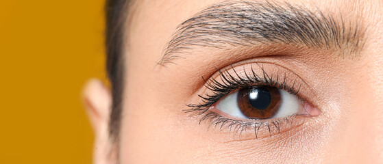 Woman with brown eyes on yellow background, closeup
