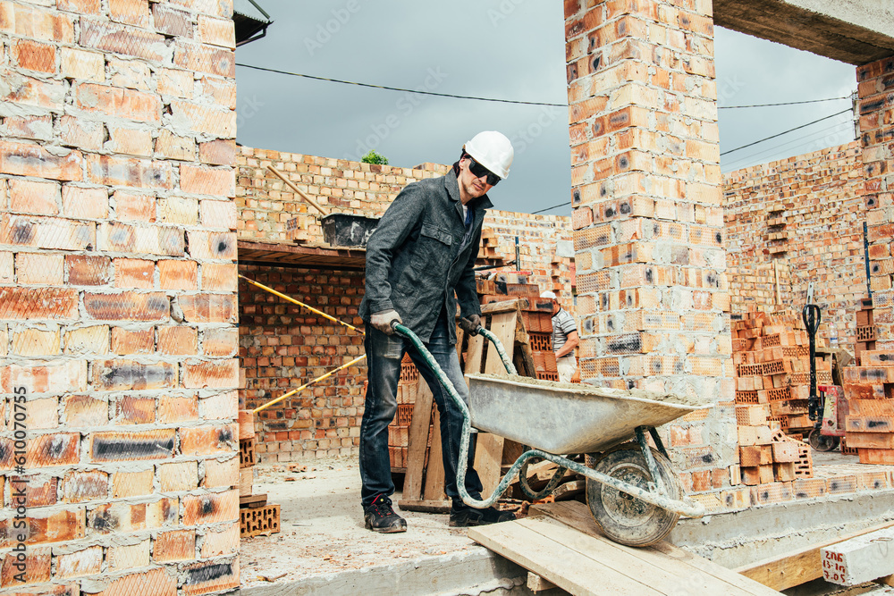 Wall mural An experienced worker works on the construction of a brick house