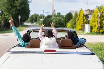 Carefree family having fun during road trip by convertible car.
