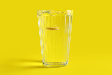 Glass of water with soluble tablet on yellow background