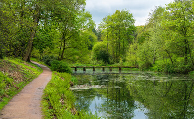 Old stone slab granite bridge across a pond or calm lake in English park land