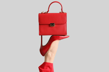 Female leg in red high heels with bag on grey background
