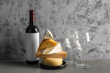 Different tasty cheese, glasses and bottle with wine on table