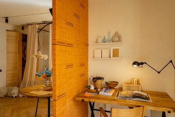 Interior view of workspace with wooden table, chair and lamp in stylish studio apartement