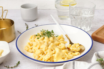 Bowl of tasty Italian pasta with Cheddar cheese on light background