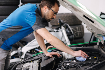 Fototapeta na wymiar Young auto mechanic check engine of car, open hood. Working outdoors 