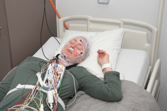 Middle aged woman measuring brain waves, examining polysomnography in sleep lab